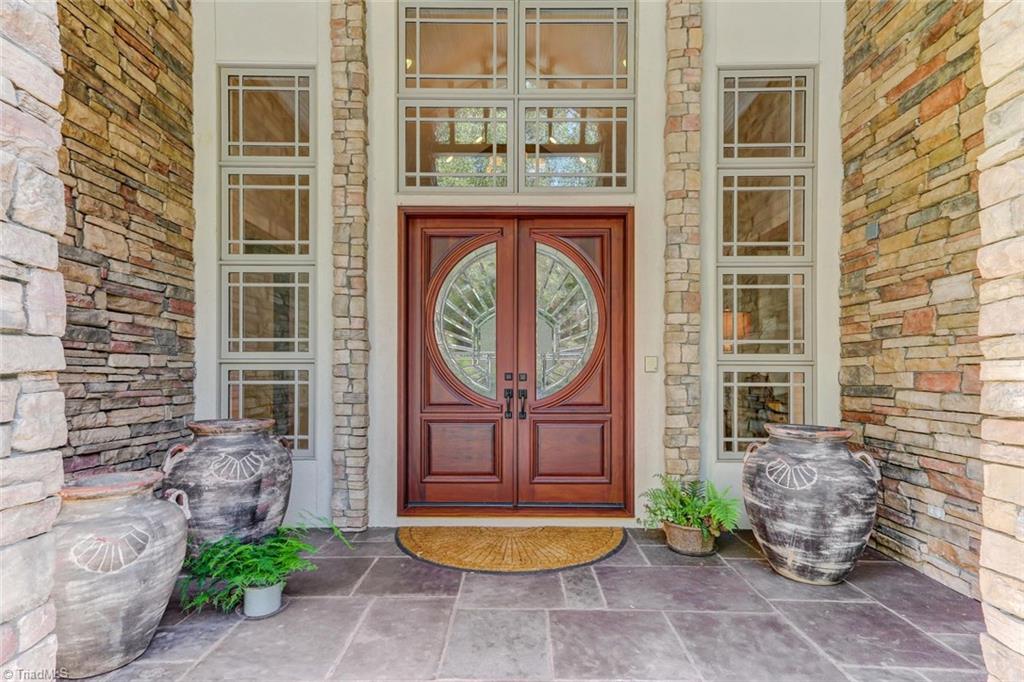 5260 Bunch Road Summerfield, NC 27358 - Photo 4 of 30 The covered entry featuring custom double doors with side lights and transom. Flagstone flooring and stone wall detail.
