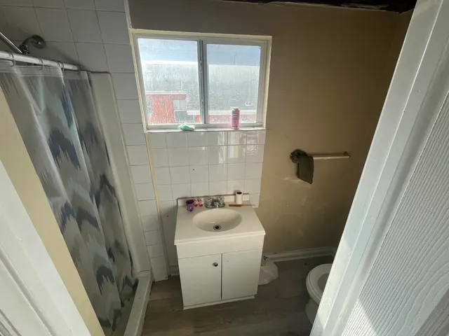 a bathroom with a sink a toilet a shower a window and vanity