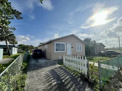 a view of a house with wooden fence next to a yard