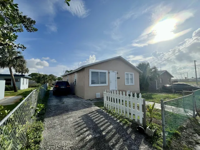 a view of a house with wooden fence next to a yard
