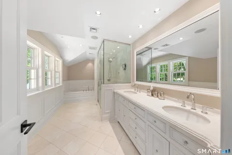 a bathroom with double vanity sinks a large mirror and a bathtub