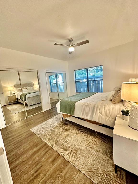 7340 Skillman Street, Unit 405 Dallas, TX 75231 - Photo 8 of 18 Bedroom featuring wood-finish flooring, a ceiling fan with integrated lighting, mirrored closet doors, and a window with exterior views