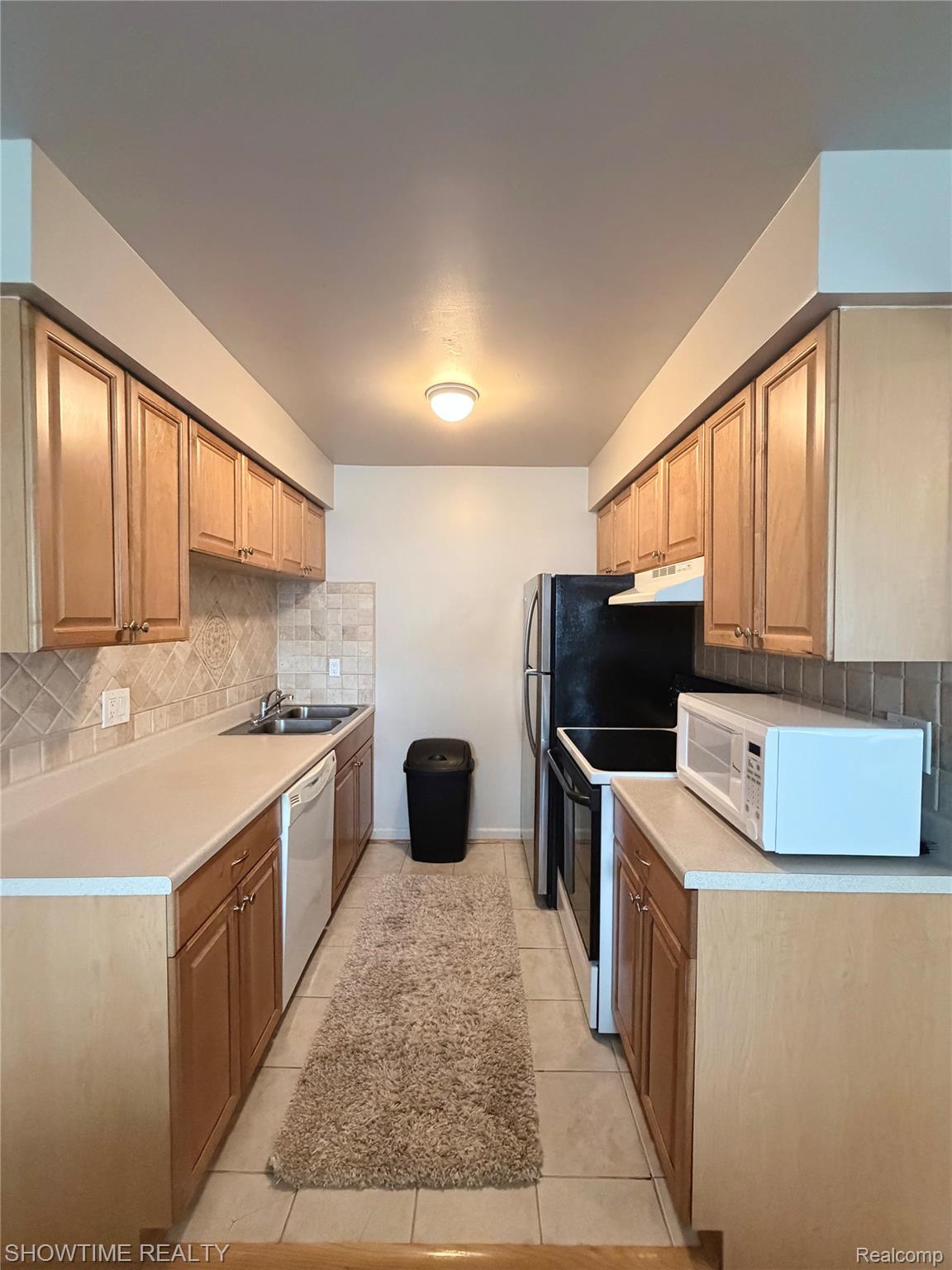 29117 Hayes Road, Unit 3 Warren, MI 48088 - Photo 7 of 14 Galley kitchen featuring light wood cabinetry, light-toned countertops, and a tiled backsplash