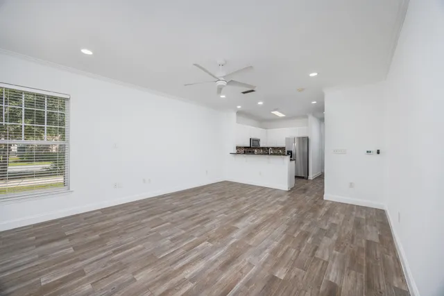 an empty room with wooden floor and a kitchen space