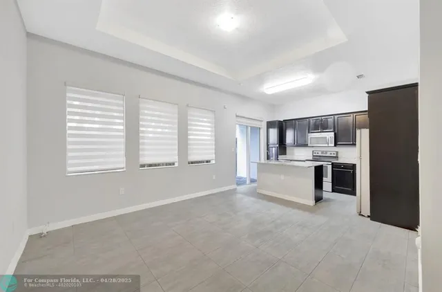 a large white kitchen with kitchen island a sink stainless steel appliances and cabinets