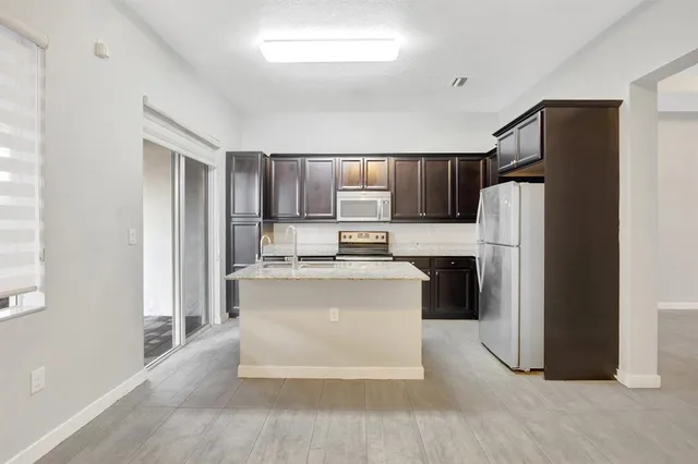 a kitchen with a refrigerator sink and cabinets