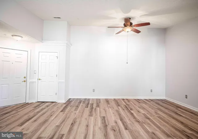 a view of a room with wooden floor and a ceiling fan