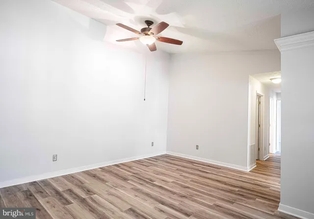 a view of a room with wooden floor and a ceiling fan