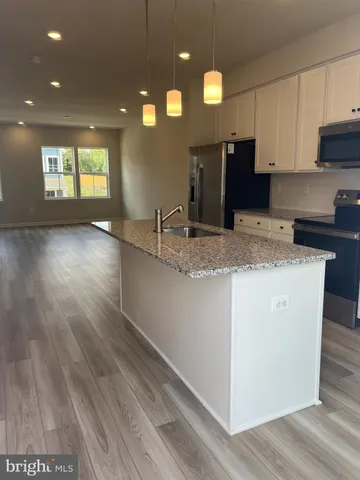 a kitchen with stainless steel appliances granite countertop a refrigerator a sink dishwasher a stove and white countertops with wooden floor