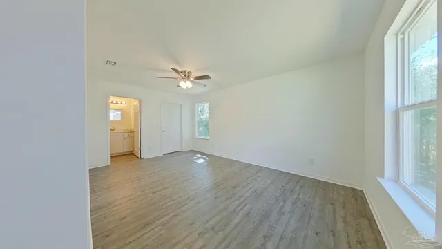 an empty room with wooden floor cabinet and windows