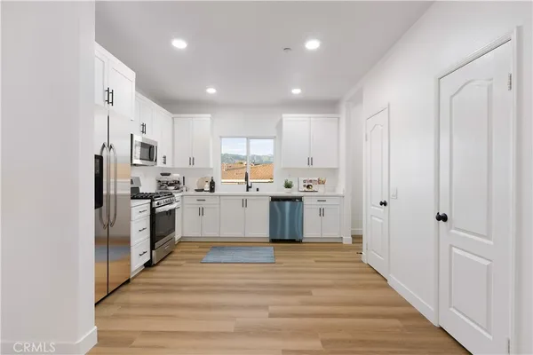 a living room with furniture a flat screen tv and kitchen view