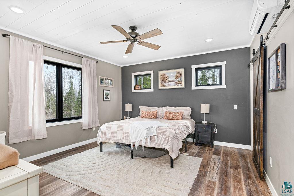 5174 Upper Peterson Road Duluth, MN 55804 - Photo 11 of 42 Bedroom with ceiling fan, dark wood-type flooring, a barn door, recessed lighting, and crown molding