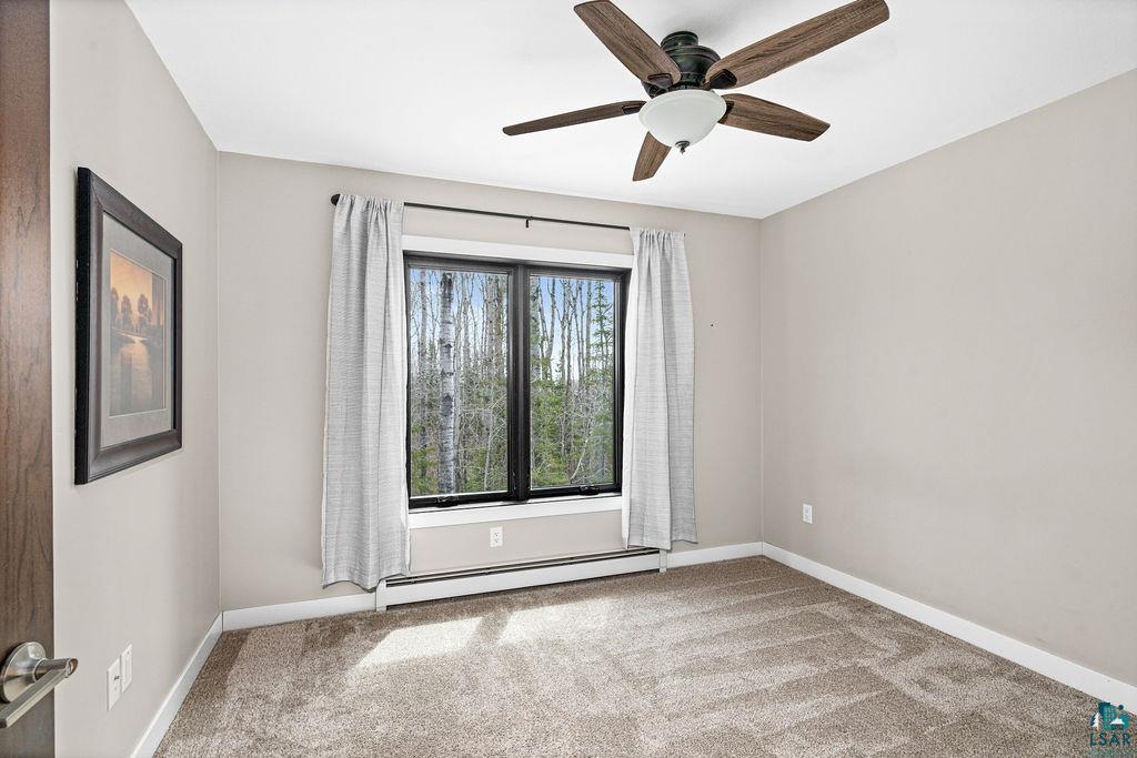 5174 Upper Peterson Road Duluth, MN 55804 - Photo 14 of 42 Empty room featuring a baseboard radiator, light carpet, and ceiling fan