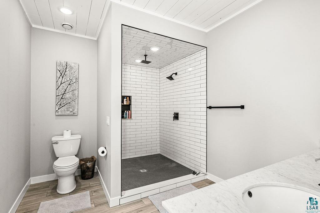5174 Upper Peterson Road Duluth, MN 55804 - Photo 16 of 42 Full bathroom featuring vanity, tiled shower, wood finish floors, ornamental molding, and recessed lighting