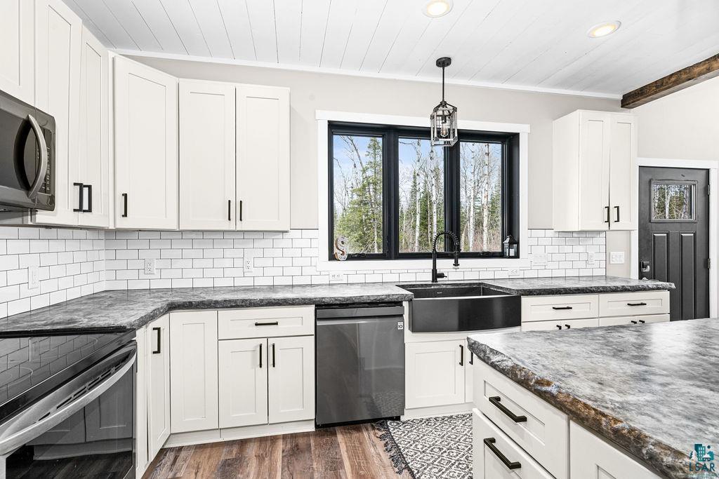5174 Upper Peterson Road Duluth, MN 55804 - Photo 21 of 42 Kitchen with hanging light fixtures, stainless steel appliances, white cabinets, crown molding, and decorative backsplash