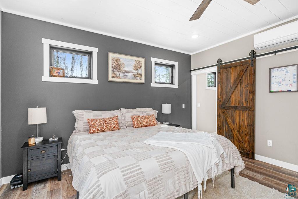 5174 Upper Peterson Road Duluth, MN 55804 - Photo 22 of 42 Bedroom featuring a barn door, wood finished floors, ceiling fan, and ornamental molding