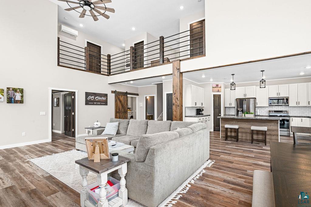 5174 Upper Peterson Road Duluth, MN 55804 - Photo 3 of 42 Living area with a barn door, dark wood finished floors, recessed lighting, a high ceiling, and ceiling fan