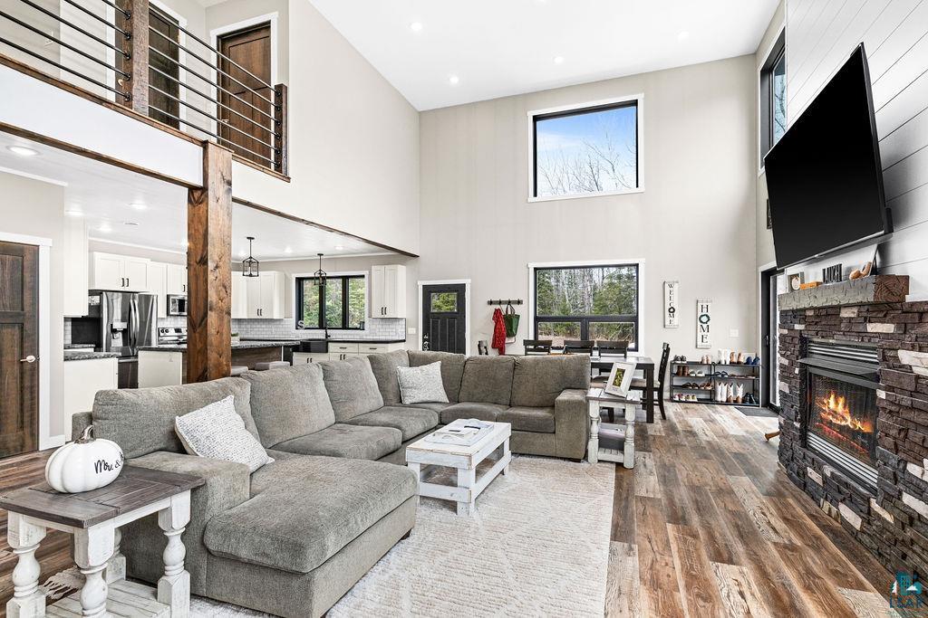 5174 Upper Peterson Road Duluth, MN 55804 - Photo 31 of 42 Living area featuring recessed lighting, a stone fireplace, wood finished floors, healthy amount of natural light, and a high ceiling