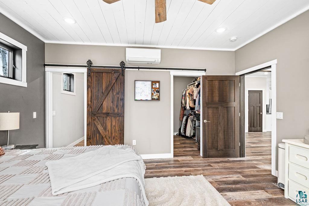 5174 Upper Peterson Road Duluth, MN 55804 - Photo 33 of 42 Bedroom featuring a walk in closet, a barn door, ceiling fan, recessed lighting, and dark wood-type flooring