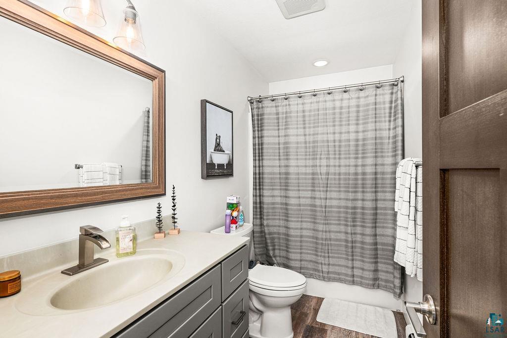 5174 Upper Peterson Road Duluth, MN 55804 - Photo 35 of 42 Full bathroom featuring vanity, shower / bath combination with curtain, and dark wood-type flooring