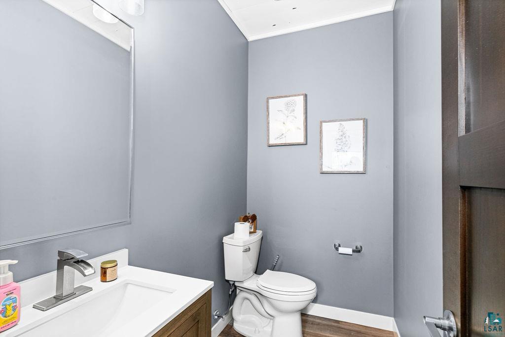 5174 Upper Peterson Road Duluth, MN 55804 - Photo 39 of 42 Half bath featuring vanity, dark wood finished floors, and ornamental molding
