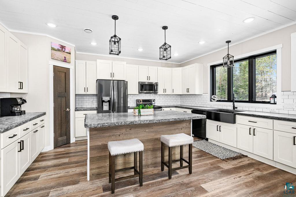 5174 Upper Peterson Road Duluth, MN 55804 - Photo 5 of 42 Kitchen featuring a kitchen breakfast bar, stainless steel appliances, white cabinetry, a kitchen island, and crown molding