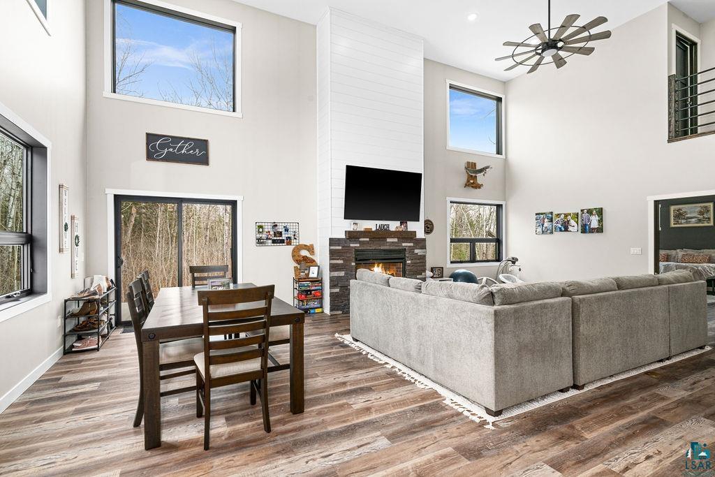 5174 Upper Peterson Road Duluth, MN 55804 - Photo 7 of 42 Living room featuring a high ceiling, wood finished floors, ceiling fan, and a lit fireplace