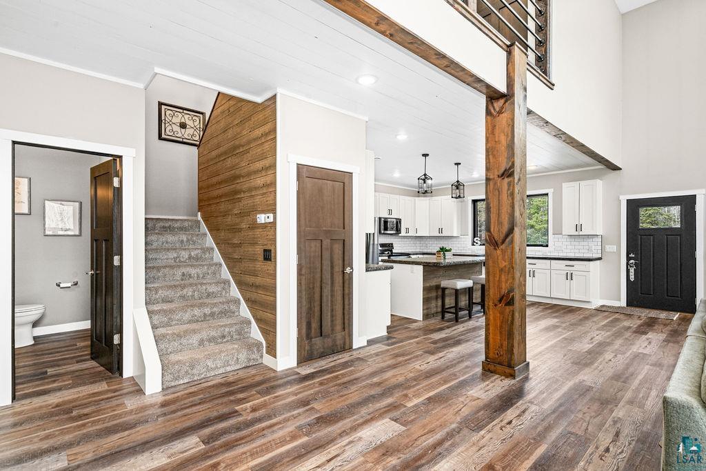 5174 Upper Peterson Road Duluth, MN 55804 - Photo 8 of 42 Kitchen with white cabinets, a breakfast bar, decorative backsplash, dark wood-style flooring, and a kitchen island