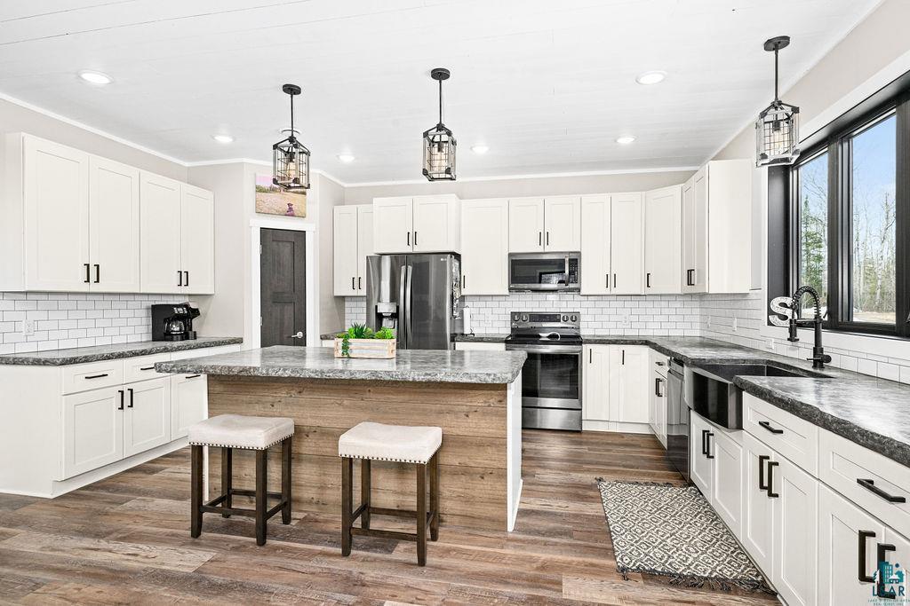 5174 Upper Peterson Road Duluth, MN 55804 - Photo 9 of 42 Kitchen featuring stainless steel appliances, pendant lighting, a kitchen bar, a center island, and backsplash