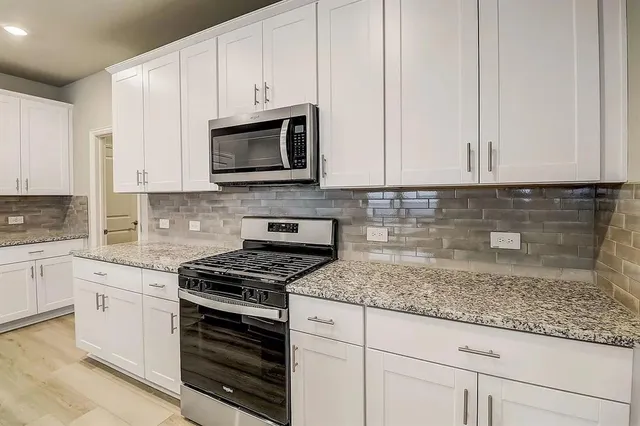 a kitchen with granite countertop white cabinets and stainless steel appliances