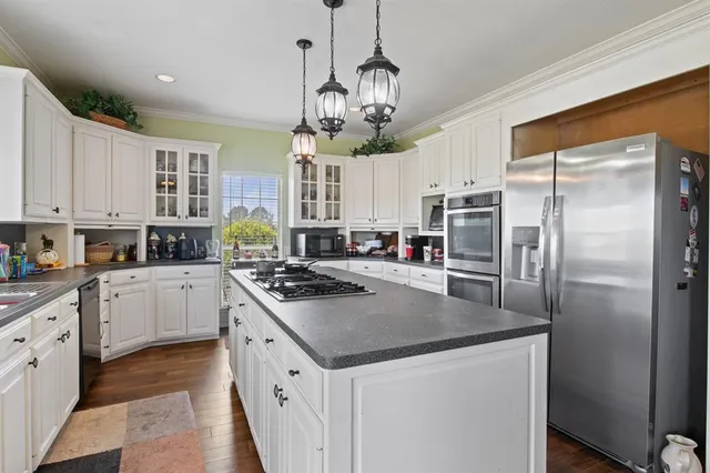 a kitchen with stainless steel appliances granite countertop a refrigerator a sink dishwasher a stove and white cabinets