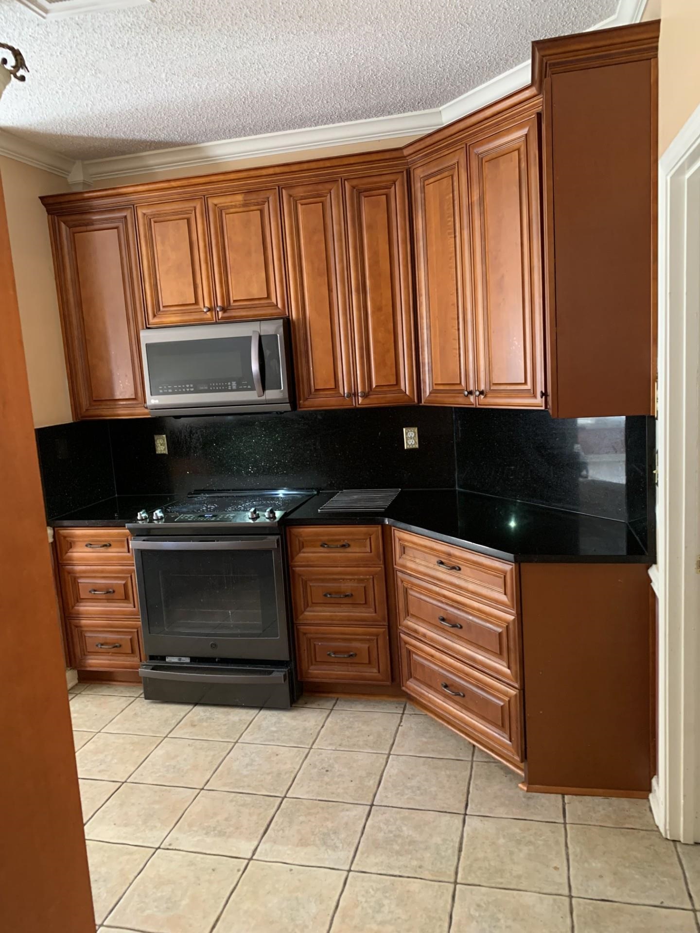 8717 Dexter Road Memphis, TN 38016 - Photo 7 of 12 Kitchen with granite countertops and backsplash, crown molding, stainless steel microwave, light tile patterned floors, and electric self cleaning range oven
