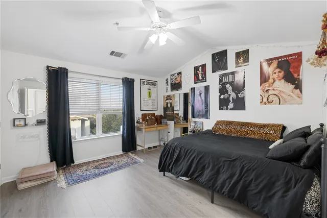 a bedroom with a bed painting on wall and a large window