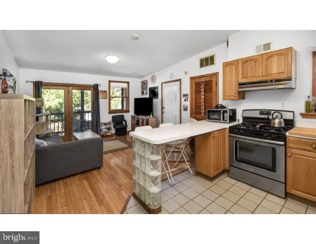 a living room with stainless steel appliances kitchen island granite countertop a stove a sink dishwasher and a microwave oven with cabinets