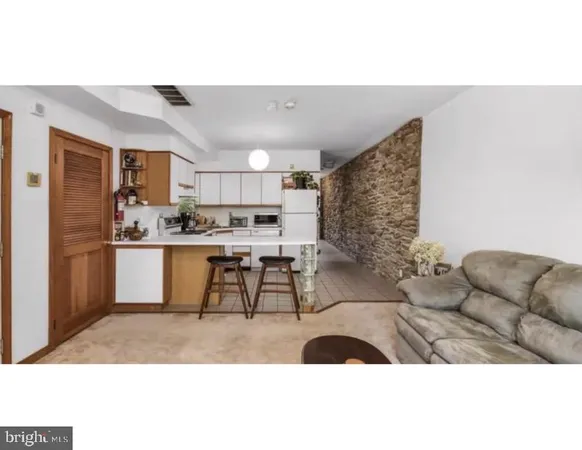 a living room with stainless steel appliances kitchen island granite countertop furniture and a couch