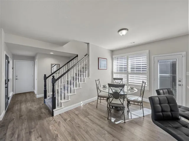 a kitchen with stainless steel appliances kitchen island granite countertop a refrigerator oven stove a sink a dining table and chairs with wooden floor