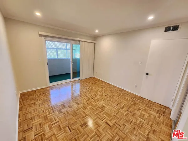 an empty room with wooden floor and natural light