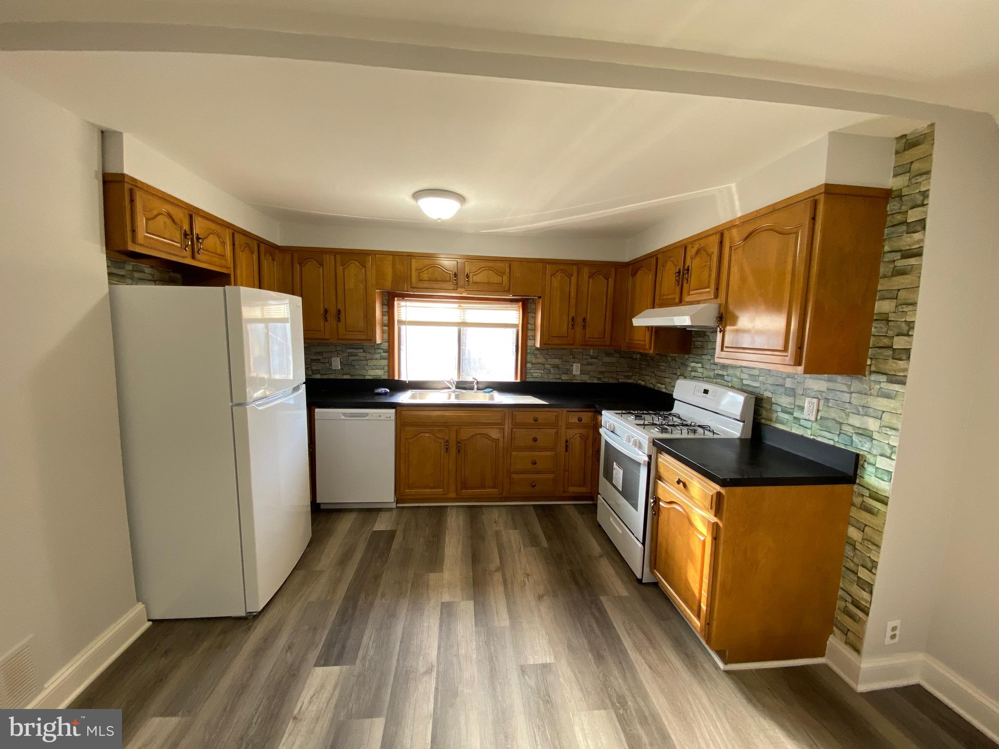 338 Gusryan Street Baltimore, MD 21224 - Photo 7 of 20 a kitchen with granite countertop a refrigerator a sink dishwasher stove and oven with wooden floor