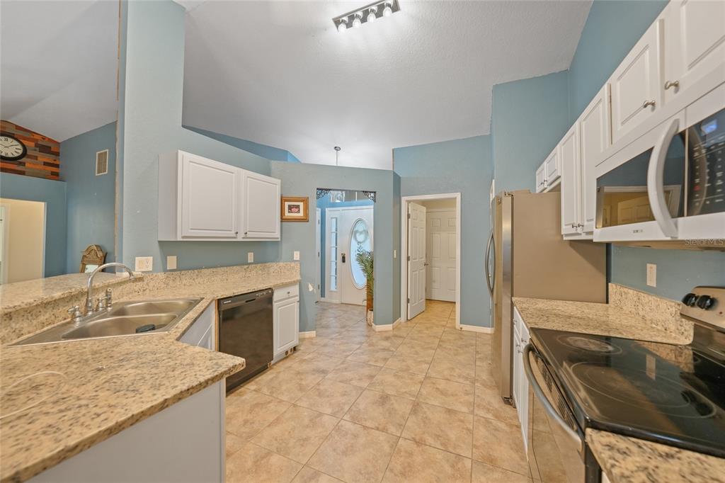 1291 Impala Street North Port, FL 34288 - Photo 15 of 44 a large kitchen with kitchen island granite countertop a sink stove and refrigerator