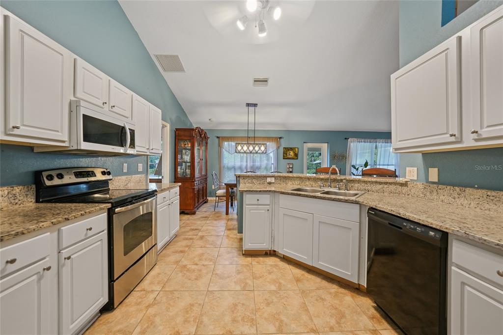 1291 Impala Street North Port, FL 34288 - Photo 16 of 44 a kitchen with stainless steel appliances granite countertop a stove top oven a sink dishwasher and a microwave oven with white cabinets
