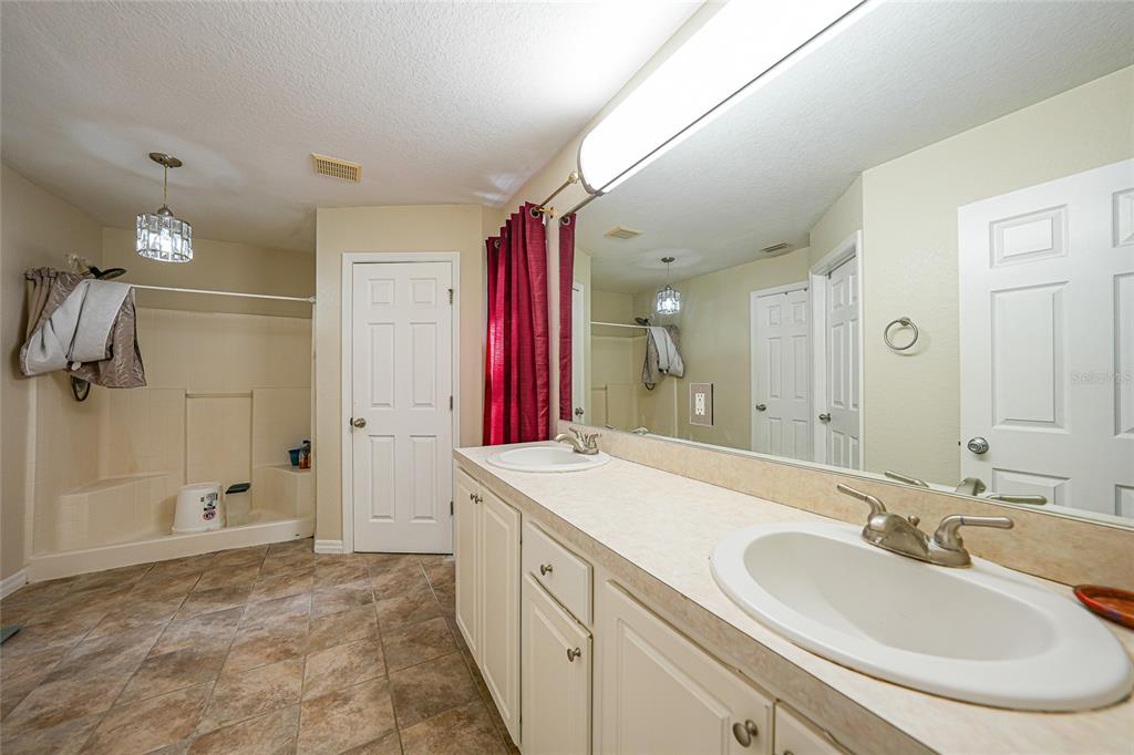 1291 Impala Street North Port, FL 34288 - Photo 21 of 44 a spacious bathroom with a sink double vanity granite tub shower and a mirror