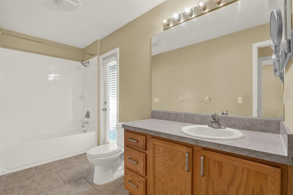 4400 Dior Road Spring Hill, FL 34609 - Photo 27 of 37 a bathroom with a granite countertop sink toilet a shower and a mirror