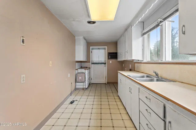 a large white kitchen with a sink a stove a refrigerator and a window