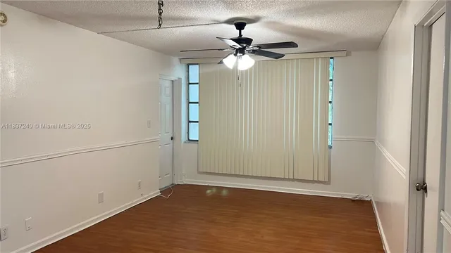 an empty room with wooden floor closet and windows