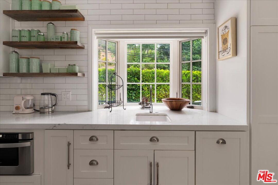 3479 Mandeville Canyon Road Los Angeles, CA 90049 - Photo 5 of 55 a kitchen with stainless steel appliances granite countertop white cabinets and a sink