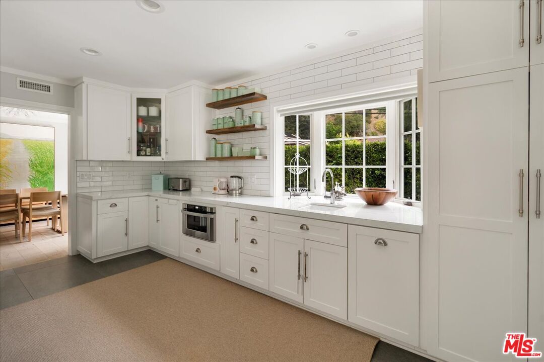 3479 Mandeville Canyon Road Los Angeles, CA 90049 - Photo 6 of 55 a kitchen with granite countertop white cabinets and white appliances