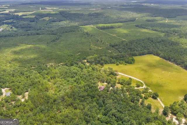 a view of a patio with table and chairs under an umbrella with large trees