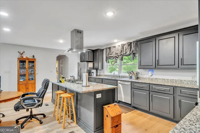 a view of a kitchen with kitchen island granite countertop a sink appliances cabinets and a counter top space