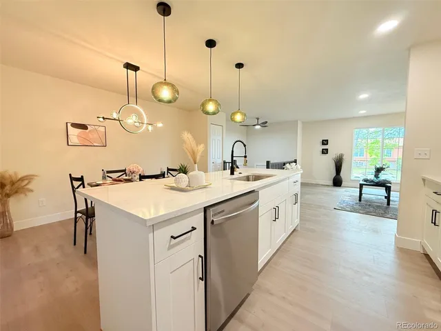 a large white kitchen with a large island oven a stove a sink a dining table chairs and couches