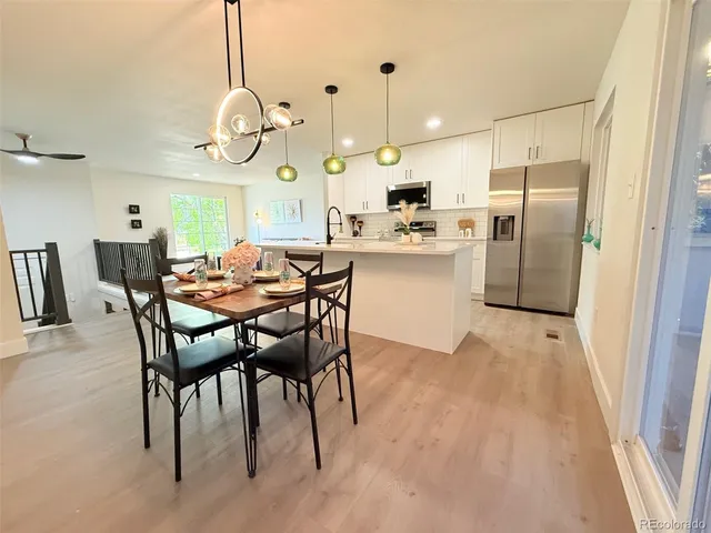 a kitchen with stainless steel appliances kitchen island granite countertop a table chairs and a chandelier